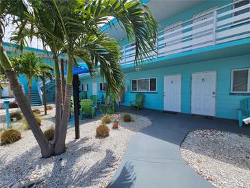 Inviting teal apartment complex featuring tropical landscaping, painted doors, and communal outdoor seating at 504 67Th Ave # 4, St Pete Beach, FL 33706