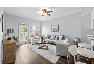 Bright living room featuring a ceiling fan, hardwood floors, stylish furniture, and a sliding glass door to the balcony at 800 S Dakota Ave # 241, Tampa, FL 33606