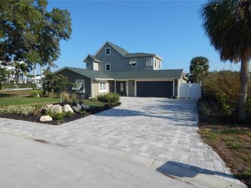Charming two-story home with a paved driveway, mature landscaping, and a two-car garage at 8025 Island Dr, Port Richey, FL 34668