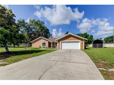 Charming single-story home featuring a two-car garage, concrete driveway, and lush green lawn at 107 Garland Cir, Palm Harbor, FL 34683