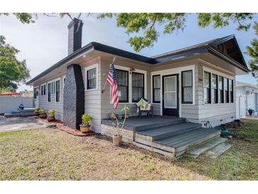 Charming home exterior featuring a quaint front porch, black chimney, and an American flag at 12595 95Th N St, Largo, FL 33773