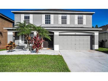 Two-story home featuring a grey color, manicured lawn, complemented by white rock and elegant tropical plants at 1712 Crossvine Ct, Trinity, FL 34655