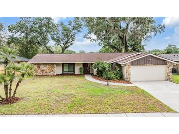 Charming single-story home with stone accents, mature trees, and a well-maintained lawn at 3604 Arlington Oaks Ct, Tampa, FL 33618