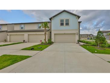 Charming townhome featuring a light blue accent above the garage and a well-manicured lawn at 7709 Imagination Pl, Wesley Chapel, FL 33545