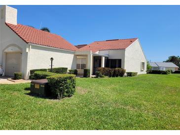 Charming home featuring a red tile roof, lush green lawn, and well-manicured landscaping at 946 Madrid Dr, Palm Harbor, FL 34684