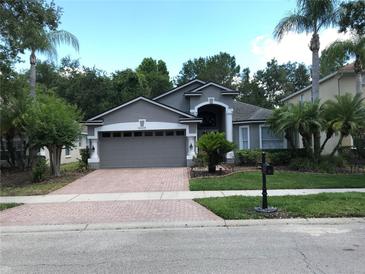 Charming gray home with a two-car garage, brick driveway and mature landscaping at 16219 Nottingham Park Way, Tampa, FL 33647