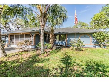 Charming single story home with blue exterior, mature trees, and manicured lawn at 2308 Rio Cir, Spring Hill, FL 34608