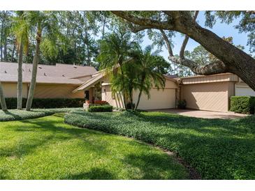 Charming home featuring well-manicured landscaping and mature trees with a two car garage at 3071 Bolt Dr, Palm Harbor, FL 34685
