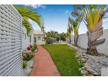 Beautiful backyard featuring a brick pathway, lush landscaping, and glimpses of a refreshing pool at 321 N Boulevard Of The Presidents, Sarasota, FL 34236