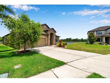 Beautiful home with a spacious driveway, green lawn, and scenic water view in a quiet neighborhood at 11878 Thicket Wood Dr, Riverview, FL 33579