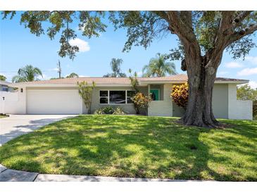 Charming single-story home boasts a well-manicured lawn and mature shade tree at 1530 Picardy Cir, Clearwater, FL 33755