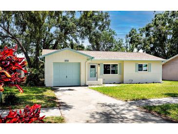 Charming single-story home featuring a well-manicured lawn, blue garage door and coordinated trim at 1573 Cumberland Ln, Clearwater, FL 33755