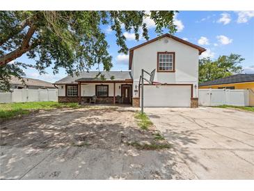 Two-story home with a white exterior, brown trim, and a front yard with a basketball hoop at 3104 Apricot St, Seffner, FL 33584