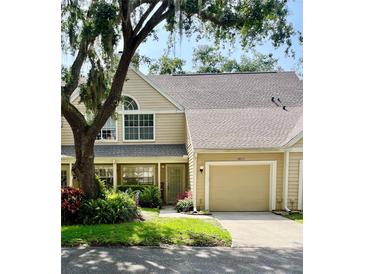 Inviting tan two-story townhome featuring an attached garage and lush landscaping at 3615 Pine Knot Dr, Valrico, FL 33596