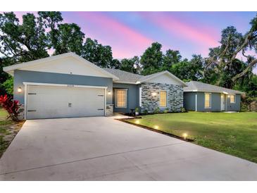 Charming single-story home showcasing stone accents, a well-manicured lawn, and an inviting two-car garage at 37230 Poinsettia Ave, Dade City, FL 33525