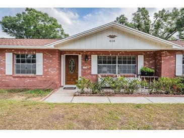 Charming red brick home featuring a well-maintained front yard, white shutters and inviting front door at 414 Cactus Cir, Seffner, FL 33584