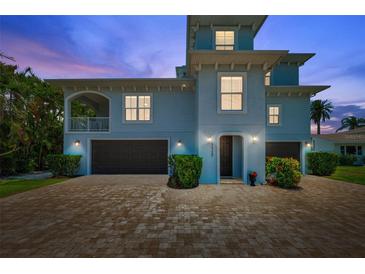 Beautiful blue two-story home with a brick driveway and well manicured landscaping at 7115 Bay St, St Pete Beach, FL 33706