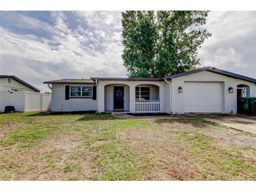 Charming single-story home with an attached garage, front yard, and white picket fence, enhancing curb appeal at 9120 Lunar Ln, Port Richey, FL 34668