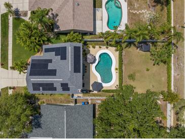 Aerial view showcasing a home with a private pool, solar panels, and lush landscaping at 1213 Barmere Ln, Brandon, FL 33511
