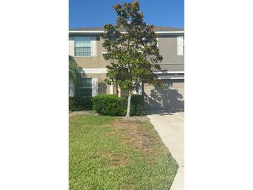 Charming two-story home featuring a well-maintained lawn and mature shade tree at 13752 Tensaw Dr, Hudson, FL 34669