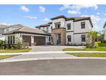 Stunning two-story home featuring a stone facade, attached two-car garage and meticulously landscaped front yard at 33750 Ocean Spray Ln, Wesley Chapel, FL 33543
