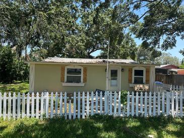 Charming home with a white picket fence and decorative wood shutters, set among mature trees at 8341 June St, Tampa, FL 33615