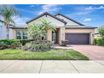 Charming single-Gathering home featuring a two-car garage, stone accents, and mature landscaping at 10415 Cardera Dr, Riverview, FL 33578