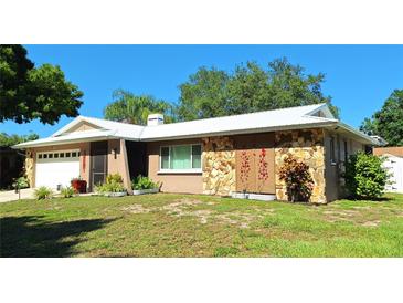 Charming single-story home featuring stone accents and a well-maintained front yard at 1291 Stony Brook Ln, Dunedin, FL 34698