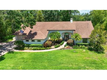 Charming single-story home with manicured lawn, mature landscaping, and a welcoming entryway at 1903 Curry Rd, Lutz, FL 33549