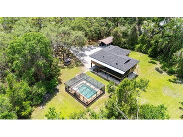 Expansive elevated home featuring a screened pool, lush landscaping, and detached carport at 35031 Shale St, Webster, FL 33597