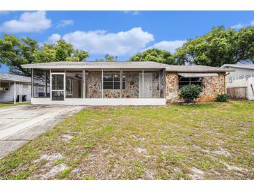 Charming single-story home featuring stone accents, a screened-in front porch, and a well-maintained lawn at 4312 Las Vegas Dr, New Port Richey, FL 34653