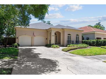 Charming home featuring a two-car garage, brick driveway, manicured landscaping, and a welcoming entrance at 4518 W Woodmere Rd, Tampa, FL 33609