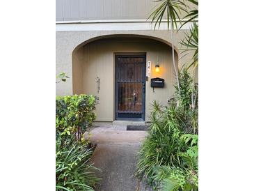 Charming front entrance with secure iron gate and lush landscaping, leading to a welcoming home at 7601 W Deleon Ct, Tampa, FL 33615