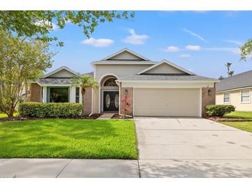 Charming single-Gathering home featuring a manicured lawn, brick accents, and a two-car garage at 9084 Quail Creek Dr, Tampa, FL 33647