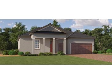 Charming single-story home featuring a welcoming front porch, a two-car garage, and a beautifully landscaped lawn at 9545 Minnow Ray Dr, Land O Lakes, FL 34638