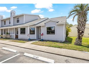 Charming exterior of gray townhouse featuring a palm tree, tidy landscaping, and well-maintained siding at 12648 Castle Hill Dr, Tampa, FL 33624
