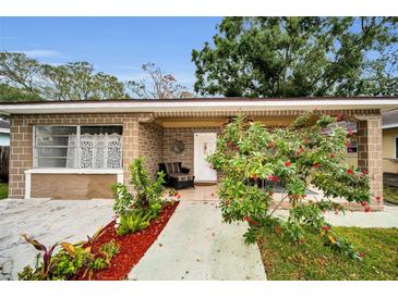 Charming single-story brick home featuring a cozy front porch with stylish outdoor seating and lush landscaping at 314 Bath St, Tarpon Springs, FL 34689