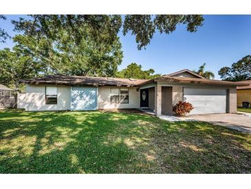 Inviting single-story home with a blue accent door, a well-kept lawn, and an attached garage at 455 Cypress Lake Ct, Oldsmar, FL 34677