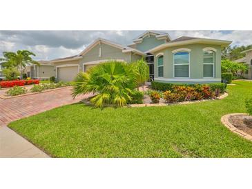Well-maintained green home featuring lush landscaping and a neatly manicured lawn at 724 Chipper Dr, Sun City Center, FL 33573