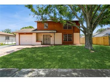 Charming two-story home featuring wood and white accents, a lush green lawn, and a mature shade tree in the front yard at 7317 W Pocahontas Ave, Tampa, FL 33634