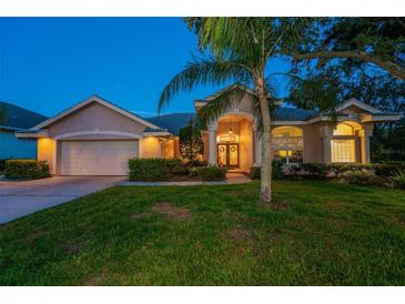Inviting single-story home featuring lush landscaping, a manicured lawn, and a charming front entrance with double doors at 1802 Oak Ridge Rd, Safety Harbor, FL 34695