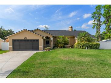 Charming single-story home with a well-manicured lawn, mature landscaping, and an attached two-car garage at 18816 Tracer Dr, Lutz, FL 33549