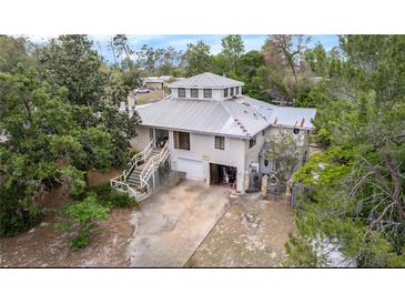 Unique two-story home with a metal roof and a two-car garage surrounded by lush greenery at 7111 Oregon Chickadee Rd, Weeki Wachee, FL 34613