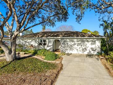Charming single-story home features a two-car garage, lush landscaping, and a mature shade tree at 8083 Bayhaven Dr, Seminole, FL 33776