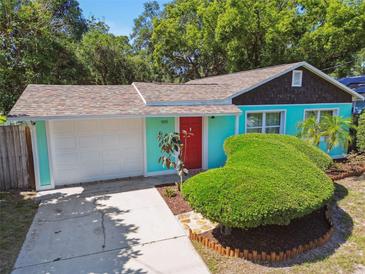 Charming turquoise house featuring a red door, green shrubbery and a well-manicured lawn at 905 8Th Sw Ave, Largo, FL 33770