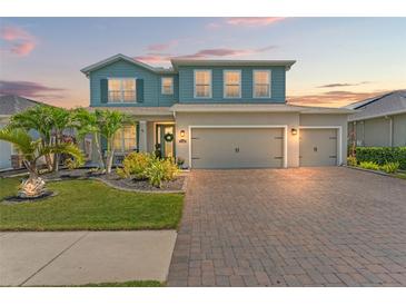 Charming two-story home features a three-car garage, brick paver driveway, and beautifully landscaped front yard at 11742 Lake Lucaya Dr, Riverview, FL 33579