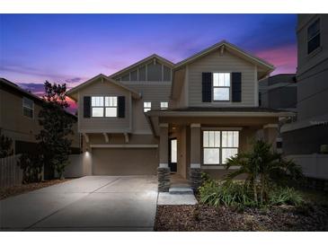 Inviting two-story home featuring a cozy front porch and well-manicured landscaping at twilight at 1520 W Fig St, Tampa, FL 33606