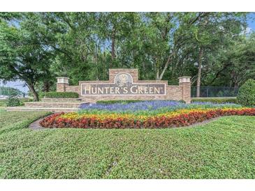 Community entrance sign for Hunter's Green amid colorful flowerbeds and lush landscaping at 18108 Ashton Park Way, Tampa, FL 33647