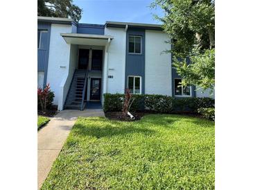 Two-story condo building features blue and white facade, landscaped yard, and a welcoming entrance at 220 Cypress Ln # 220, Oldsmar, FL 34677