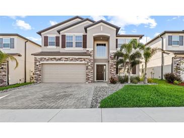 Charming two-story home featuring a stone facade, manicured lawn, and paver driveway at 3071 Marine Grass Dr, Wimauma, FL 33598